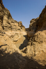 The dry bed among the high steep conglomerate cliffs of the narrow Sesriem canyon in the Namib...