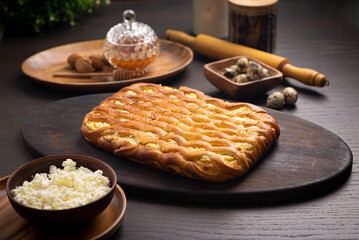 Curd pie on a fluffy ruddy dough on a dark wooden table