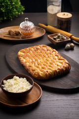 Curd pie on a fluffy ruddy dough on a dark wooden table