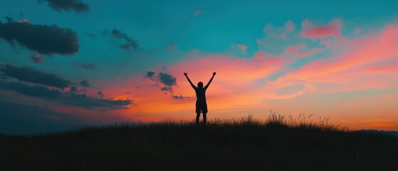 Obraz premium Silhouette of a person celebrating at sunset with vibrant colors in the sky, capturing joy and freedom in natures beauty.