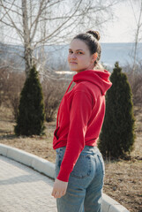 Fototapeta premium Casual outdoor portrait of a young woman in red hoodie for lifestyle design