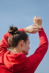Young woman in red hoodie enjoying sunny day outdoors with clear sky