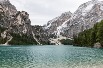 Obraz premium Calm turquoise waters of Lake Braies reflect dramatic peaks and forested slopes, offering a scenic alpine landscape in South Tyrol, Italy