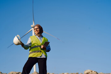 Muslim Woman Engineer Posing in Front of Wind Turbines for Electricity Generation.