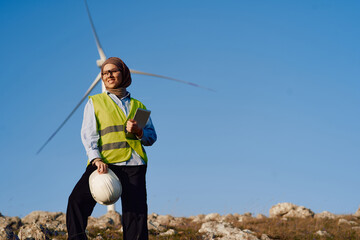 Muslim Woman Engineer Posing in Front of Wind Turbines for Electricity Generation.