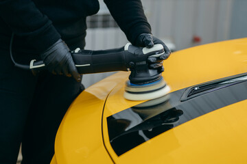 Process of polishing yellow sport car in workshop