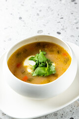 A bowl of delicious soup garnished with fresh cilantro on a textured surface, featuring vibrant vegetables and a creamy swirl, perfect for showcasing comforting culinary delights