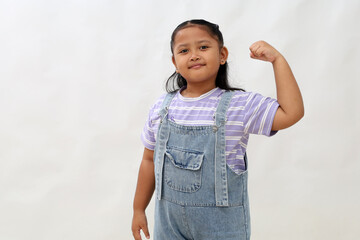 Happy asian little girl standing while showing strong hand gesture. Isolated on white background