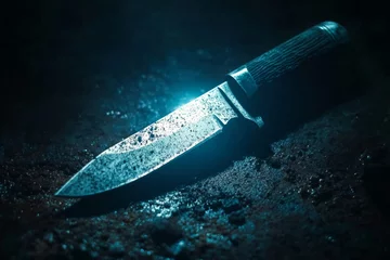 Fotobehang Close-up of a rusty hunting knife on a dark, textured surface, illuminated by dramatic lighting, creating a mysterious and suspenseful atmosphere © Michael