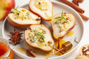 Baked pears with cheese, nuts and honey in a plate on the table.