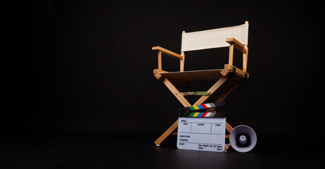 White director chair with clapper board and megaphone on black background.