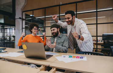 Group of cheerful colleagues celebrating success in office
