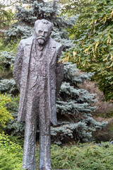 A large bearded statue stands prominently in front of trees