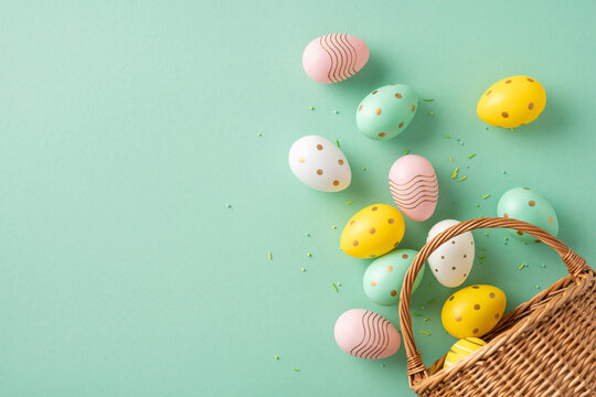 Colorful decorated Easter eggs placed near a wicker basket on a green surface, embodying the festive and joyful vibe of Easter celebrations