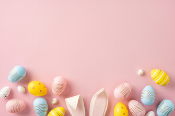 Decorative pastel Easter eggs and bunny ears arranged on a pink surface in a festive layout