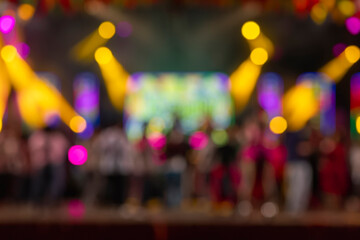 Blurred concert stage with colorful spotlights and crowd in the background