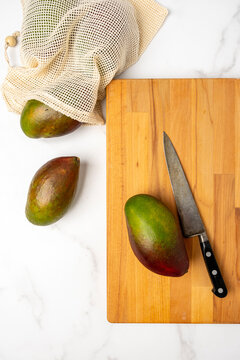 Mangos on a cutting board with knife 