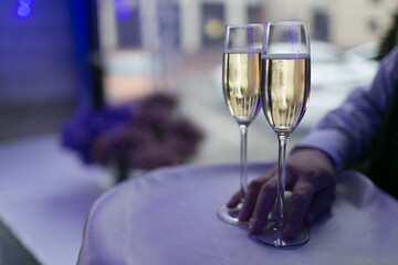 A person is elegantly holding two glasses of champagne that are placed on a table, ready for a celebratory toast or drink sharing
