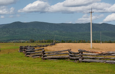 Russia. The Republic of Buryatia. View of fields in the valley of the Irkut river enclosed by wooden fences of a special zigzag structure made of logs.