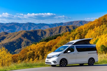 Naklejka premium A white campervan with a pop-top roof is parked overlooking a scenic autumnal mountain landscape