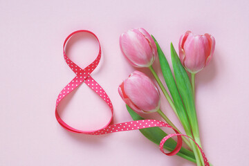 Number eight from a ribbon and a bouquet of tulips on a pink background. Postcard for International Women's Day, March 8
