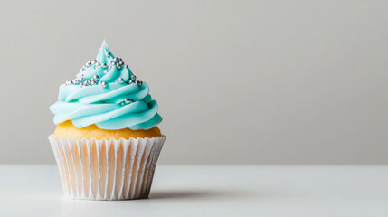 Delicious vanilla cupcake with blue frosting and silver sprinkles on white background. Concept of sweet indulgence, dessert, celebration, bakery treat. Copy space