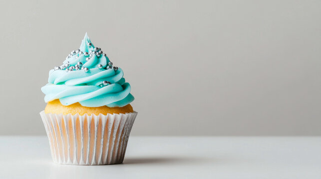Delicious vanilla cupcake with blue frosting and silver sprinkles on white background. Concept of sweet indulgence, dessert, celebration, bakery treat. Copy space