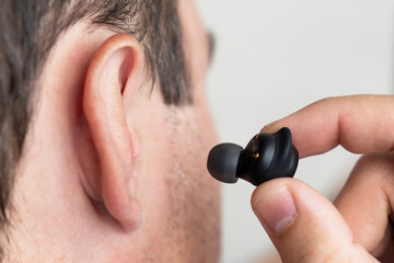 Close-up of wireless earphone in human ear on white background. insert earphone into the ear