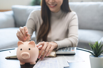 Saving money wealth concept, asian young business woman hand putting coin into piggy for saving...