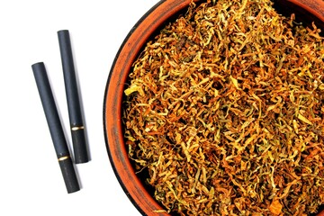 Fermented yellow tobacco in a brown plate on a white background and two cigarettes