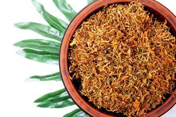 Fermented yellow tobacco in a brown plate on a white background with green leaves