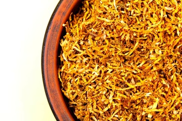 Fermented yellow tobacco in a brown plate on a white background