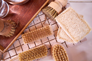 A variety of wooden dish and cleaning brushes rest on a tile countertop, close-up view from above