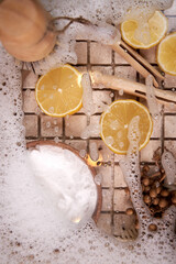 Close-up of natural fiber brush, dishwashing foam, lemon wedges, top view