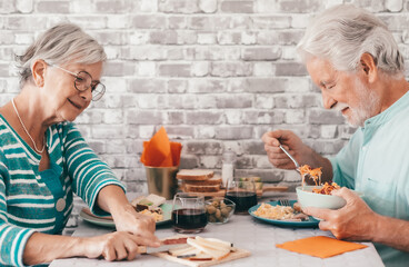 Smling carefree caucasian senior couple sitting at table having a brunch together at home enjoying an healthy eating together