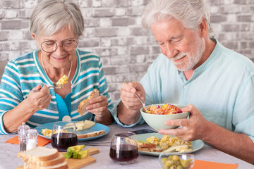 Smling carefree caucasian senior couple sitting at table having a brunch together at home enjoying...