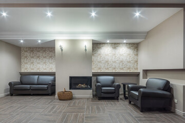 Exclusive interior of the living room with fireplace in a luxury chalet. Stylish leather furniture. Interior decoration in pastel colors.