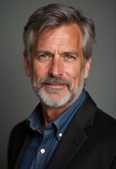 Fototapeta premium A mature man with gray hair, resident of USA, smiles gently. The warm lighting creates a cozy atmosphere. Calm, confident look. Experience, professionalism and intelligence in the eyes. Generative AI