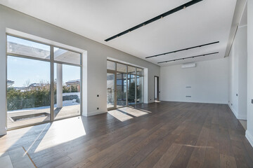 A large room with panoramic windows in a luxurious mansion. Winter sunny landscape outside the window. Unfurnished.