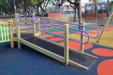 Inclusive playground for children with functional diversity and physical disabilities. Detail of the ramp leading up to the play area with bright and fun colours. Rubber flooring with shapes.