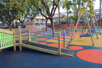 Inclusive playground for children with functional diversity and physical disabilities. Detail of the ramp leading up to the play area with bright and fun colours. Rubber flooring with shapes.