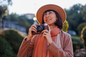 Fashionable look. a young woman with a film camera walks along the street. Hipster tourist woman...