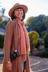 Fashionable look. a young woman with a film camera walks along the street. Hipster tourist woman...