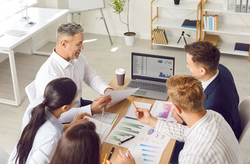 Business team doing data analysis during work meeting. Group of people sitting together at office...