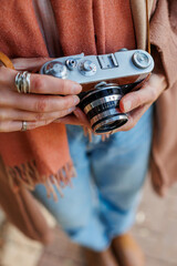 Fashionable look, young woman with film camera. Hipster tourist woman holding a camera in her...