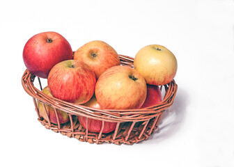 Ripe, natural red and pink apples in a basket on a white isolated background.