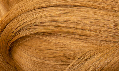 Red hair close-up as a background. Women's long orange hair. Beautifully styled wavy shiny curls. Hair coloring bright shades. Hairdressing procedures, extension.