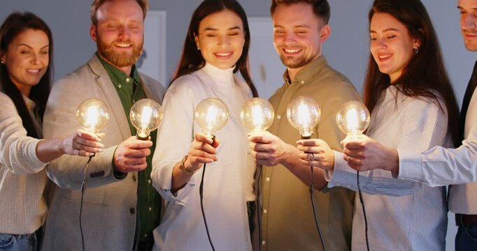Group portrait of a diverse business team holding glowing light bulbs and smiling. Creativity, innovation, imagination, inspiration and collaborative work in a business environment.