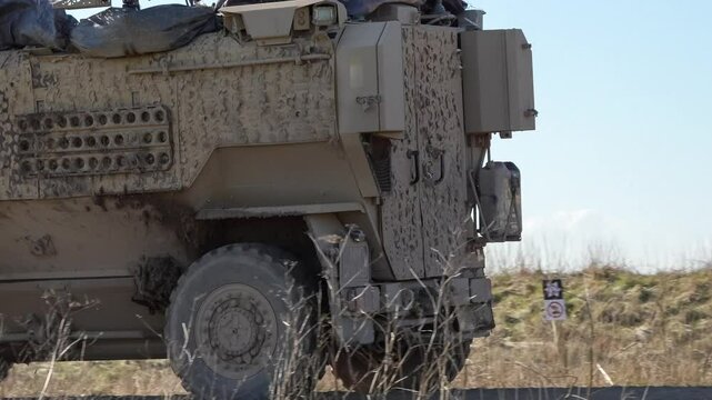 a pair of British army Foxhound four wheeled utility vehicles at speed on a dirt track