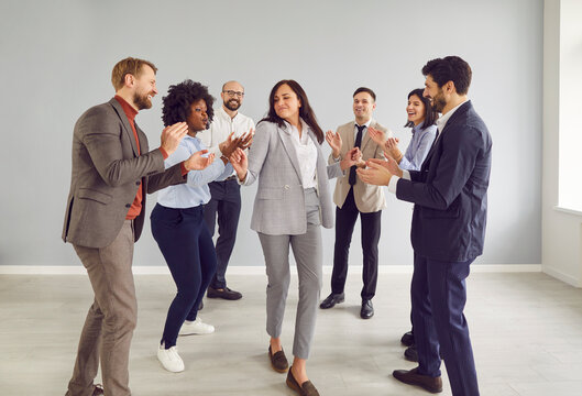 Team of colleagues in the office celebrates success by dancing and applauding during a work meeting. Group demonstrates teamwork and enthusiasm while working together in a collaborative environment.